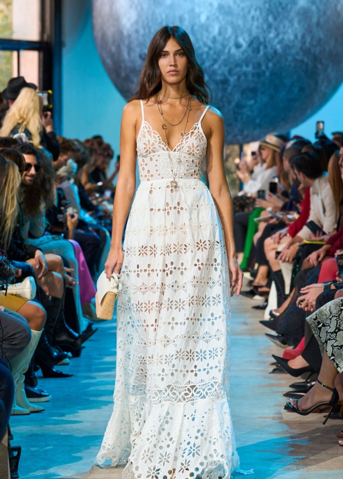 فستان أبيض بوهيمي وحقيبة من القش من مجموعة إيلي صعب ربيع صيف 2024