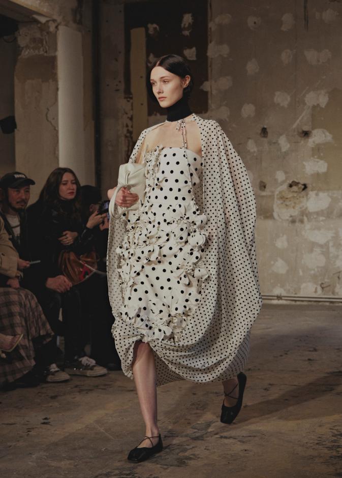 فستان من Rokh بقصة غنيّة بالطيات، يجمع بين اللون الأبيض الأساسي والنقشة المرقطة بالأسود، لإطلالة رومانسية كلاسيكية