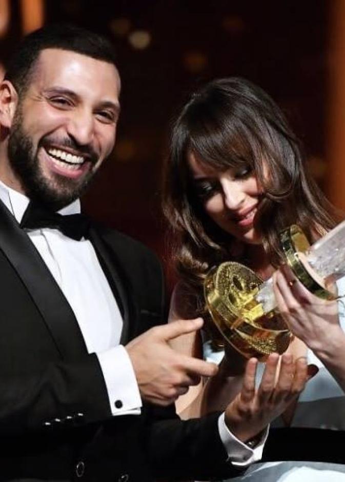 لقطة ضاحكة بين داكوتا جونسون والتونسي نضال السعدي أثناء تسليمه جائزة أفضل ممثل في اختتام مهرجان مراكش للفيلم