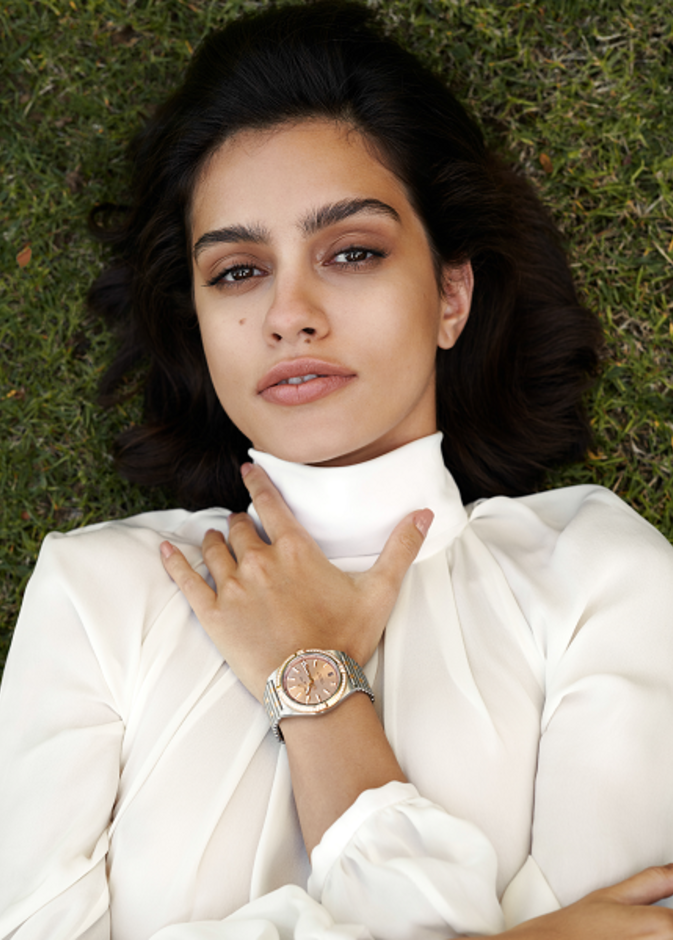 ساعة كرونومات أوتوماتيك 36 Chronomat Automatic 36 من الفولاذ المقاوم للصدأ والذهب الأحمر عيار 18 قيراطا، ومزدانة بمجموعة من الأحجار الكريمة وميناء نحاسي. من دار "بريتلينغ" Breitling. قميص من "جيني" Genny.