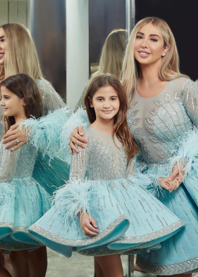 جويل ماردينيان وابنتها بالفستان الأزرق القصير المزيّن بالشكّ الراقي والريش على الأكمام