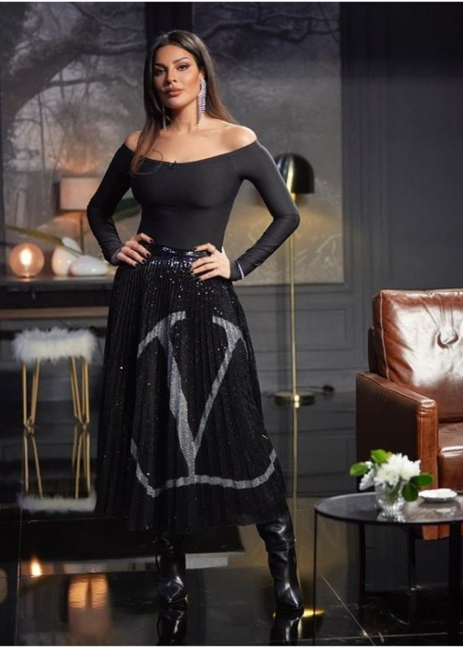 إختارت تنورة ميدي من ماركة فالنتينو  تميّزت بالترتر اللامع باللون الأسود مع لوغو الدار