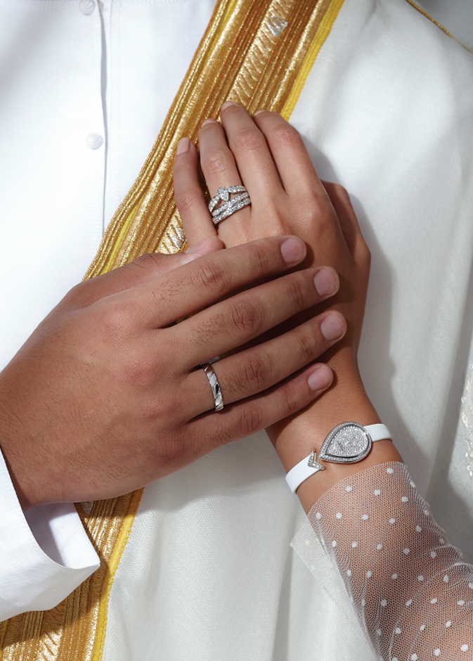 ساعة "جوزفين إيغريت" Joséphine Aigrette من الذهب الأبيض وبإطار مرصع بأحجار من الماس بالقطع اللمّاع، وميناء أبيض منقوش، وسوار من الساتان الأبيض. خاتما "جوزفين أوب برينتانيير" Joséphine Aube Printanière من البلاتين، مرصعان بالماس بالقطع اللمّاع، وقد رصع أحدهما بماسة على شكل إجاصة. على إصبع الرجل: خاتم "تورساد دو شوميه" Torsade de Chaumet من البلاتين. من "شوميه" Chaumet.