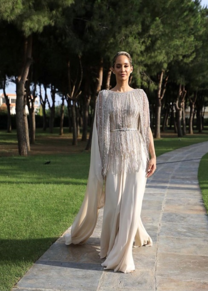 جامبسوت باللون العاجي مرفق بكاب طويل ومزيّن بالشراشيب المرصّعة باللؤلؤ