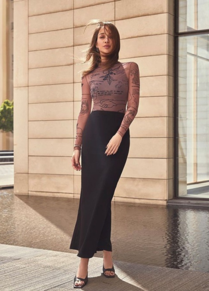 نسّقت التنورة الماكسي الضيقة بقصة الخصر العالي مع التوب الضيقة والمزيّنة بالرسمات والكتابات