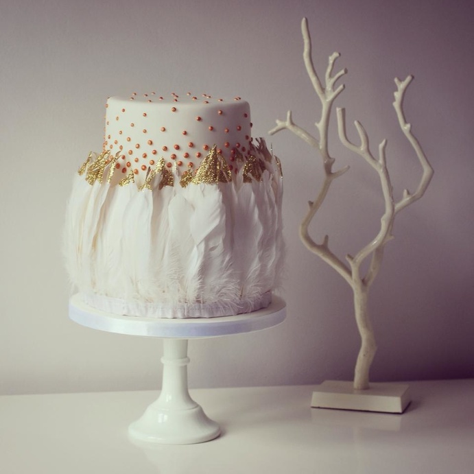 كعكة زفاف بيضاء ذات طبقة واحدة فقط مغطاة بالكامل بحبيبات ذهبية لامعة.