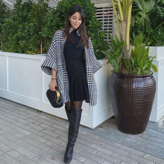 أسيل بالفستان الأسود ونسّقت معه المعطف الأنيق باللونين الأبيض والأسود وأكملت اللوك بالجزمة ذات الساق العالية