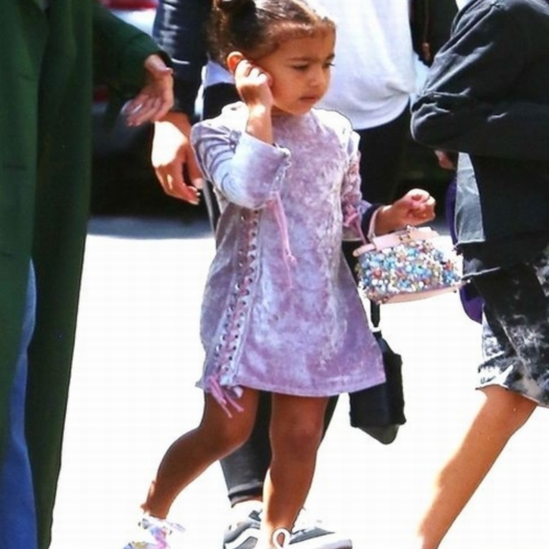 اطلالة رائعة لنورث ويست في فستان قصير من المخمل مزين لربطات جانبية نسقته مع شنطة يد من فندي وحذاء رياضي ملون