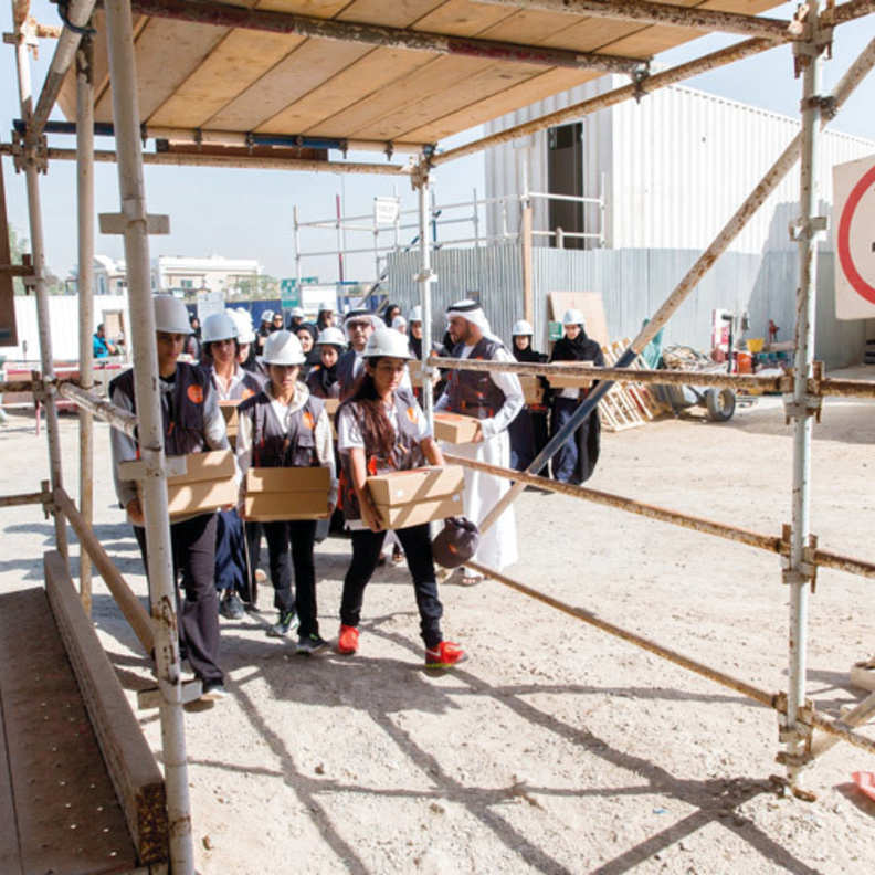 شما بنت محمد وطلاب مدارس في دبي يوزعون الطعام على العمال