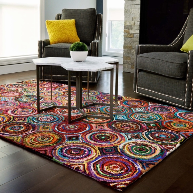 على الأرضية الخشب و اللون الرمادي للكنب لا شيء أجمل من سجادة ملونة بألوان مشرقة