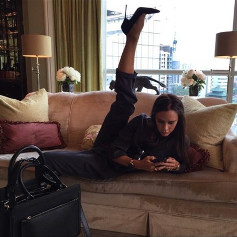 فيكتوريا بيكهام تمدد قدمها مرتدية الكعب العالي فيما تطالع هاتفها الجوال