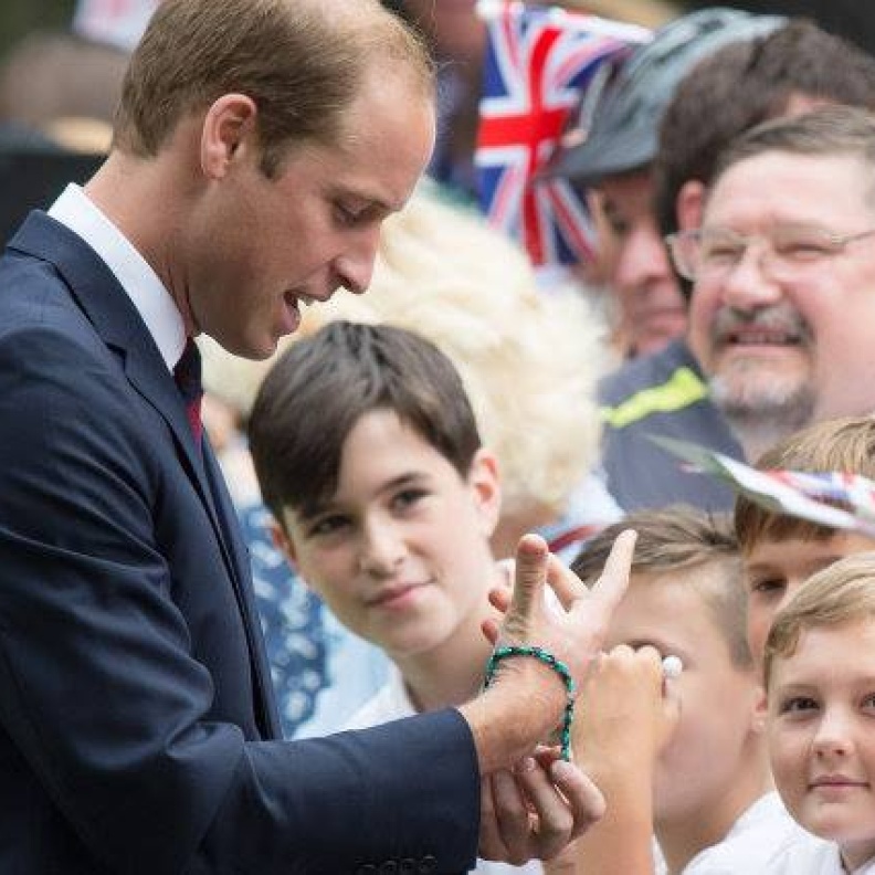 الأمير ويليام يجرب أحد الأساور التي قدمت له من أحد المعجبين اللذين تجمعوا للقائه في حديقة Coventry's War Memorial