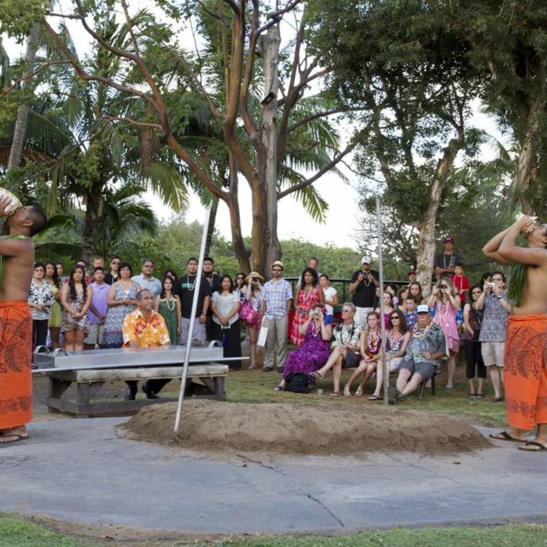 Attractive young men in traditional Hawaiian dress play seashell