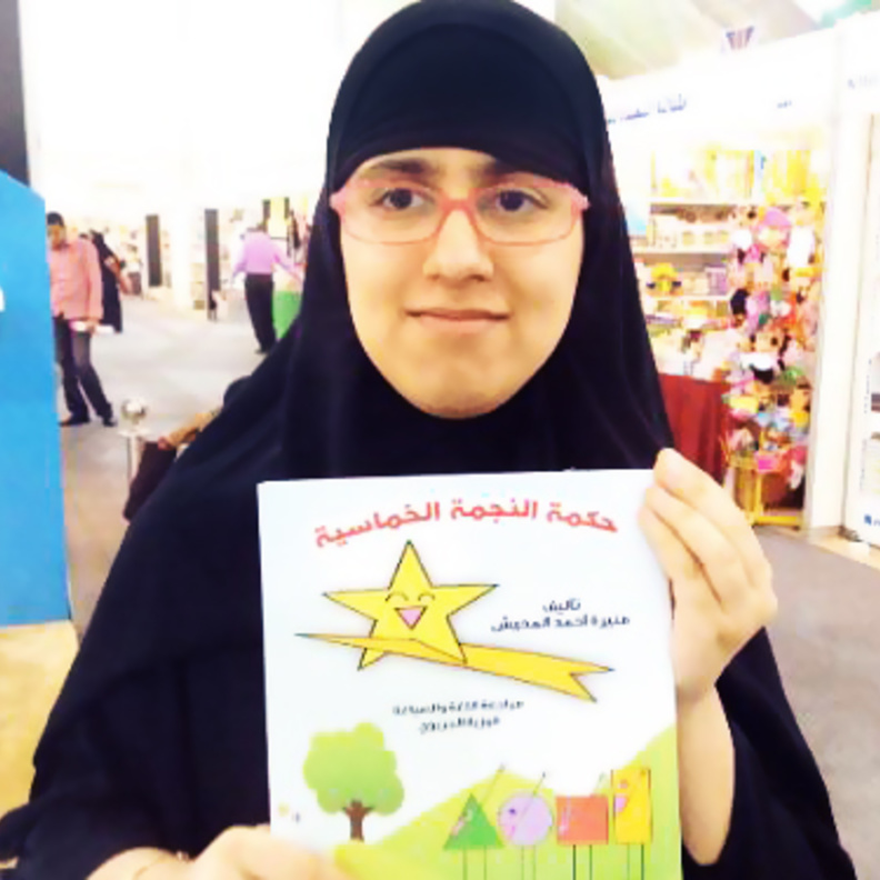 منيرة تمسك بكتابها حكمة النجمة الخماسية