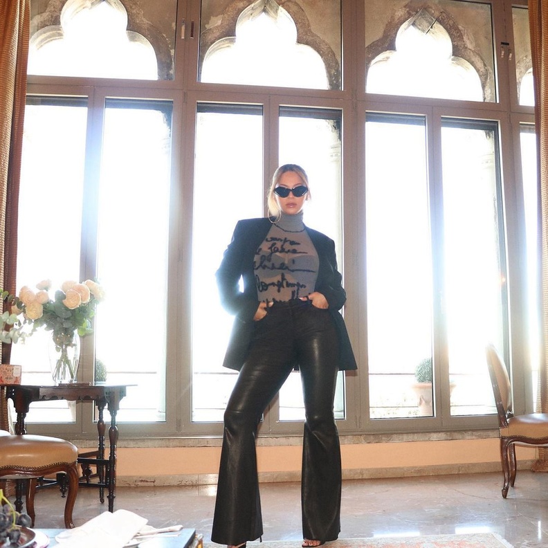 نسّقت البليزر الجلد الطويلة والبنطلون بقصة الأرجل الـflare مع التوب الشفاف