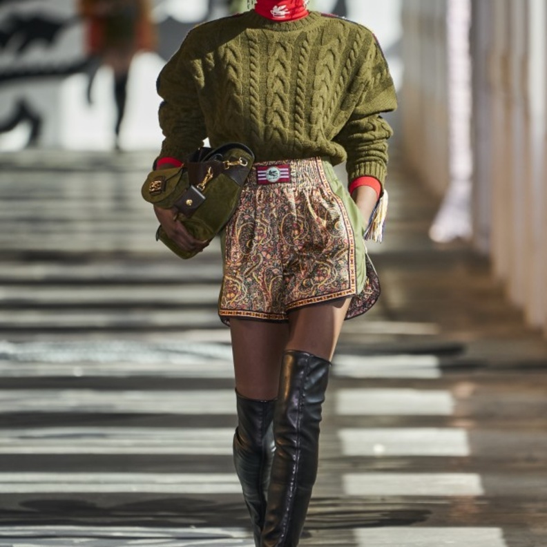 إختاري البلوفر باللون الزيتي نسقي تحته التوب الأحمر بياقة عالية مع الشورت القصير