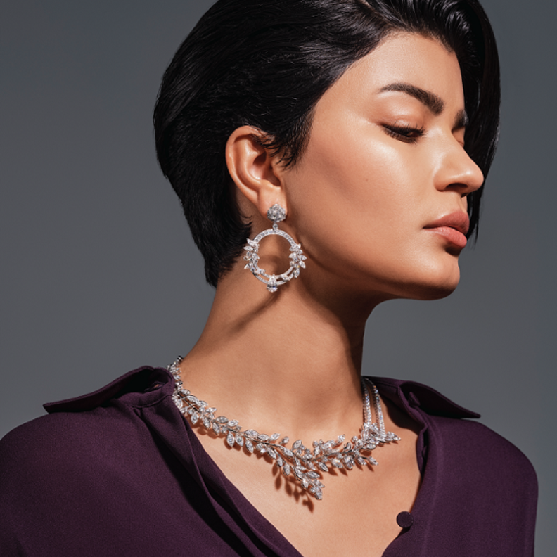 أقراط "لايملايت روز باشن" Limelight Rose Passion وعقد "لايملايت غاردن بارتي" Limelight Garden Party من الذهب الأبيض والماس من دار "بياجيه" Piaget للمجوهرات الفاخرة. قميص من تنسيق منسّقة الأزياء.