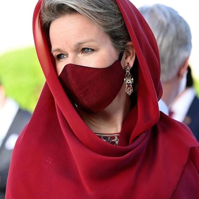 ملكة بلجيكا بإطلالة حمراء وغطاء رأس خلال زيارة مسجد السلطان قابوس