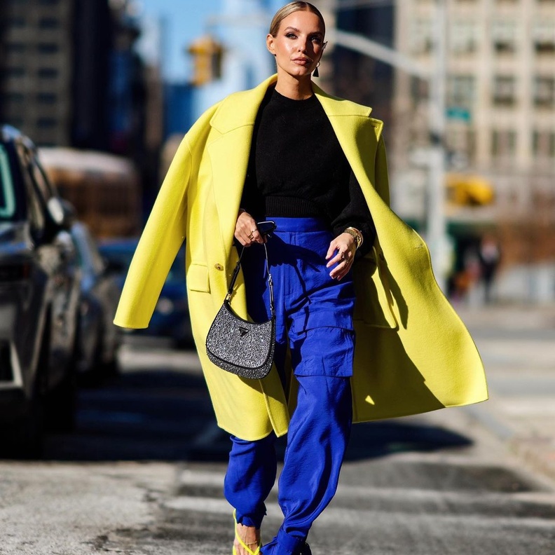 تألقت بالمعطف الأصفر الذي  نسّقته مع التوب الأسود والبنطلون الواسع باللون الأزرق