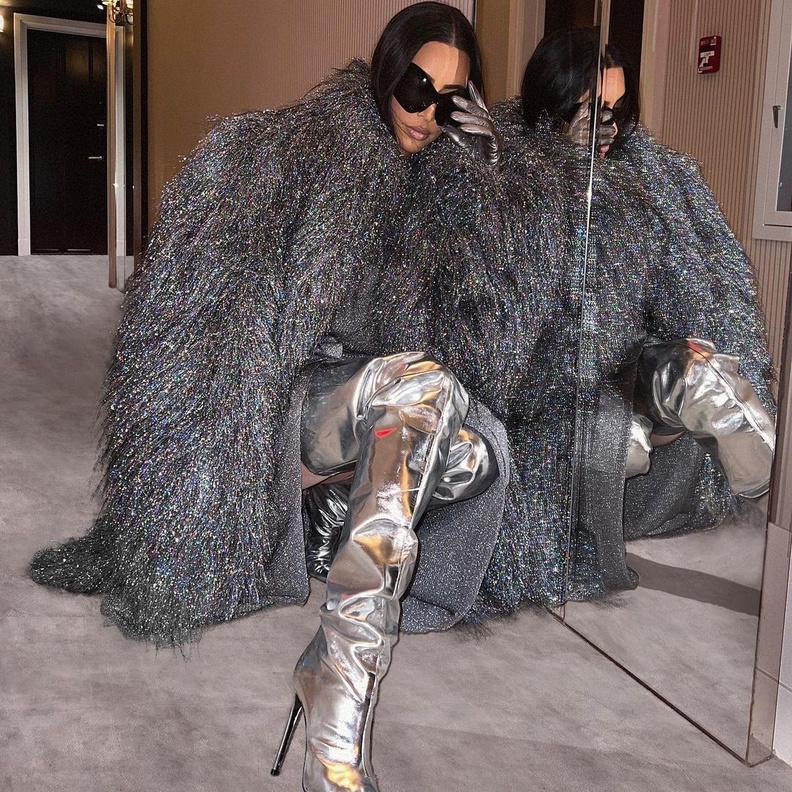 تألقت كيم بالمعطف الفضي نسقت معه فستان رمادي فاتح وجزمة ميتاليكية