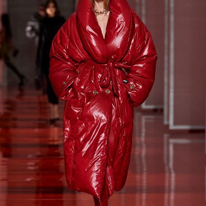 Versace جمعت بين التصاميم المنتفخة واللامعة في معطف أحمر مع الحزام ليحدد الخصر