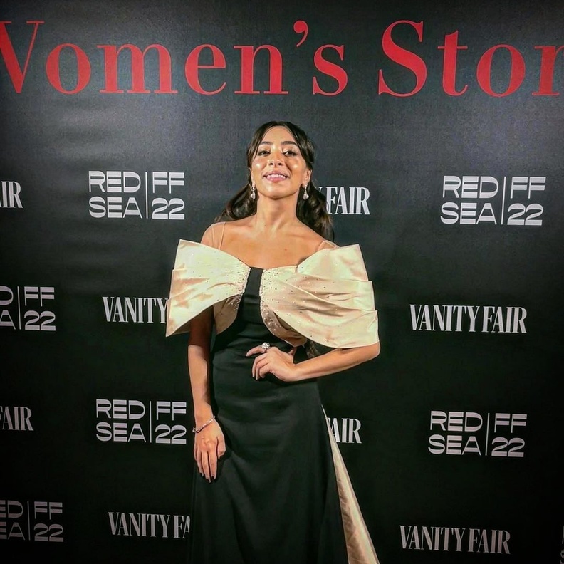 الممثلة السعودية سارة طيبة ترتدي فستانًا راقيًا باللون الأسود بأكتاف منسدلة باللون البيج من إلوستريلا في مهرجان البندقية السينمائي