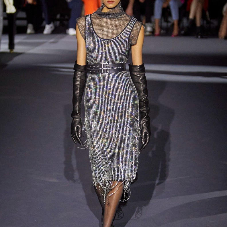 فستان ميدي باللونين الأسود والفضي ذو لمسات معدنية وبرّاقة، وحزام جلدي أسود، وقفازات