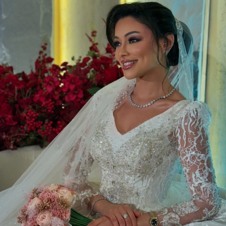 شوق الهادي أول عروس في مسلسلات رمضان 2025..كيف بدت إطلالتها؟  عندليب دندش الإطلالات الأنيقة التي تتميز بها الفنانة الكويتية شوق الهادي إنعكست على رقي إختيارها في إطلالتها العرائسية في المسلسل الرمضاني لعام 2025 أبو البنات، إذ توجهت لاختيار فستان زفاف بموضة القصات المنفوشة ذات التنورة الضخمة والقماش المطرز بالترتر على عكس فستان زفافها في مسلسل أمينة حاف الذي عُرض في رمضان 2021 والذي اعتمد على قماش الساتان وجاء بتفاصيل جداً بسيطة وناعمة باستثناء اليدين التي تم إدخال حركة إليهما على هيئة خيوط لامعة تربط أسفل ا