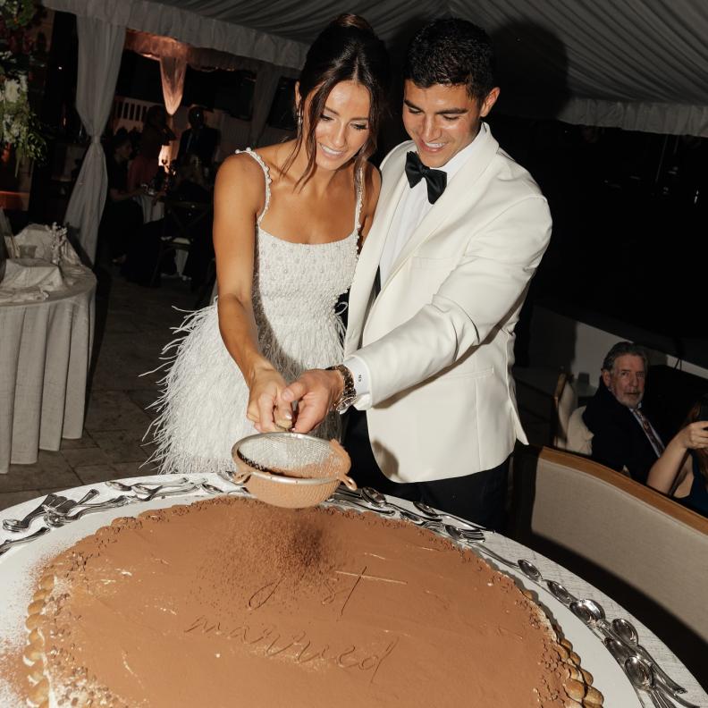 عروسان يقومان بتزيين الكيك مباشرة ليلة الزفاف أمام الضيوف