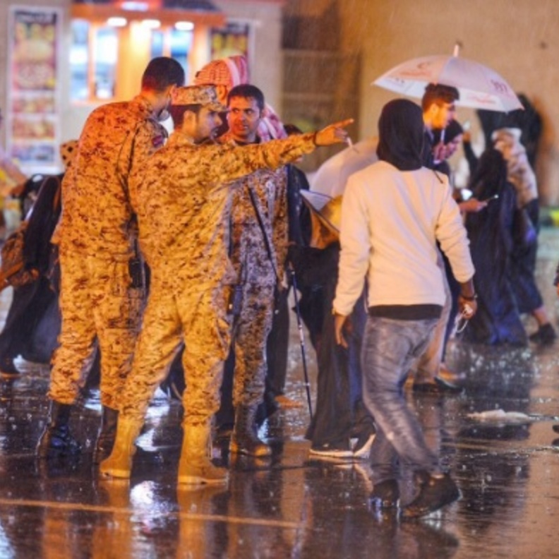 صورة مؤثرة..رجل أمن سعودي يحمي مسنة من الأمطار بملابسه الخاصة