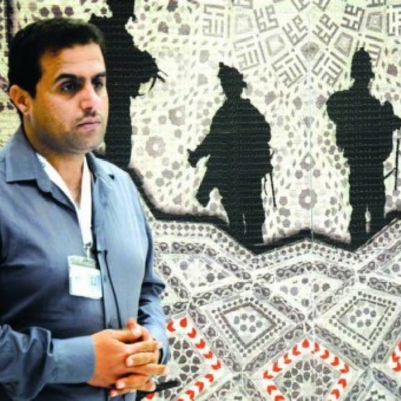 الفنان بجانب إحدى لوحاته