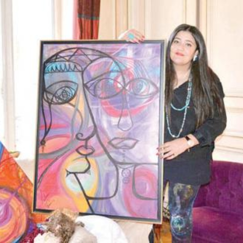 الفنانة مع احدى لوحاتها