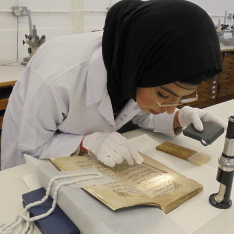 فاطمة الضيف اثناء اداء عملها بترميم الأعمال الفنية