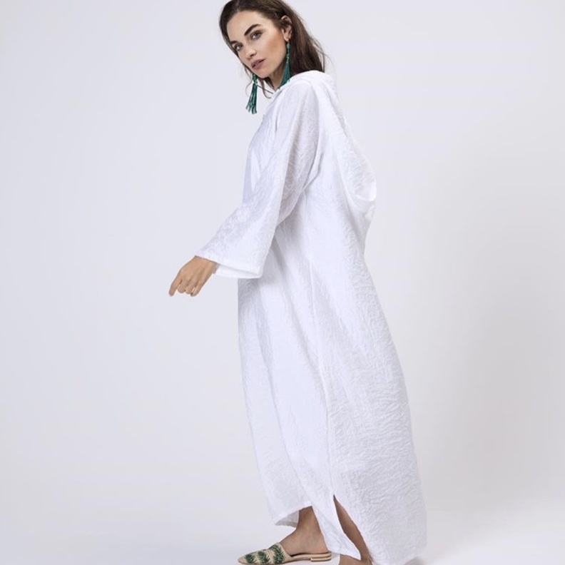 قفطان أبيض مع حزام طويل باللون الأخضر محكم بحلقة معدنية .