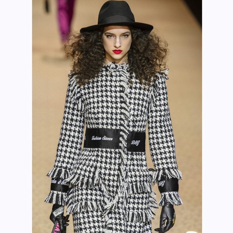 صورة مقرّبة للمعطف بالأسود والأبيض المكلّل بشراشيب باللون الأسود