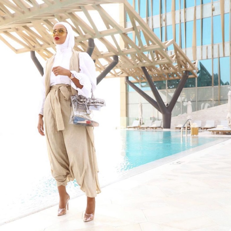 نسقي القميص الزهير مع البنطلون الأبيض وحقيبة من ديو