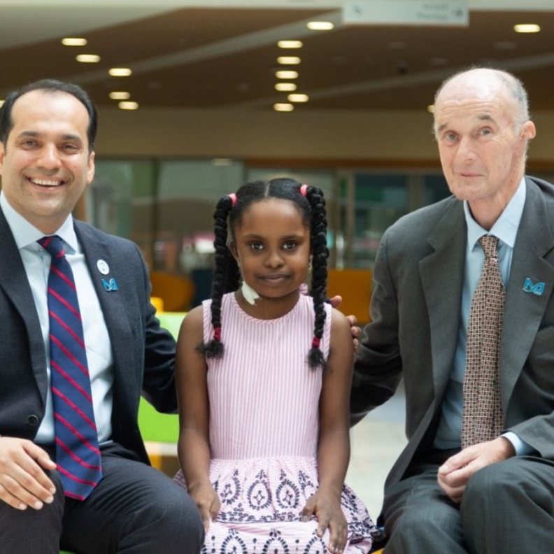 الطفلة السودانية وسط أسرتها والفريق الطبي المعالج لها 