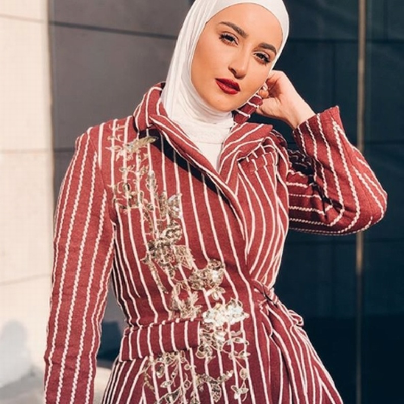 اختارت دلال الدوب بليزر أسود أنيق مع حزام ونسّقته مع حجاب أبيض مزيّن بلمسات ناعمة