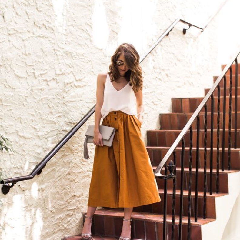 استوحي اطلالاتك الكاجوال بتنانير الميدي الجذابة مع التيشرت والأحذية الرياضية