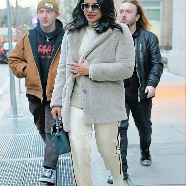 أطلت بسروال من قماش الساتان مع كنزة ومعطف قصير من الفرو الناعم باللون الرمادي الفاتح