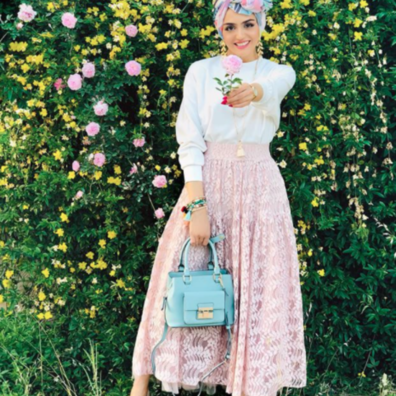 جاذبية غادة عثمان بالتنورة الدانتيل الزهرية مع التوب الأبيض والاكسسوارات باللون الأزرق