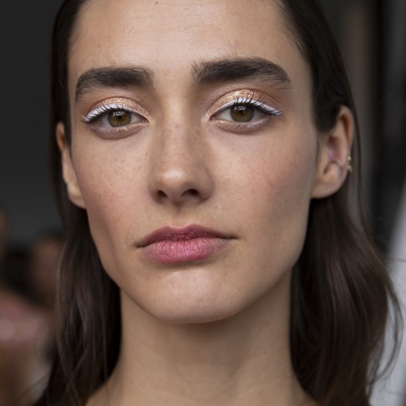 استوحي من Pamella Roland الآيلاينر الأبيض الناعم الذي يزين الجفون البرونزية