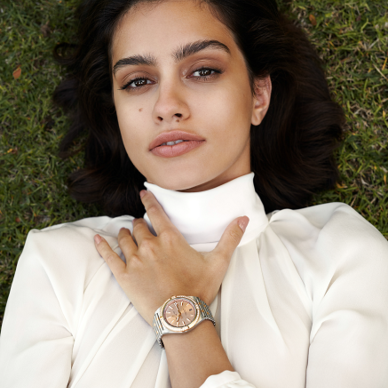 ساعة كرونومات أوتوماتيك 36 Chronomat Automatic 36 من الفولاذ المقاوم للصدأ والذهب الأحمر عيار 18 قيراطا، ومزدانة بمجموعة من الأحجار الكريمة وميناء نحاسي. من دار "بريتلينغ" Breitling. قميص من "جيني" Genny.