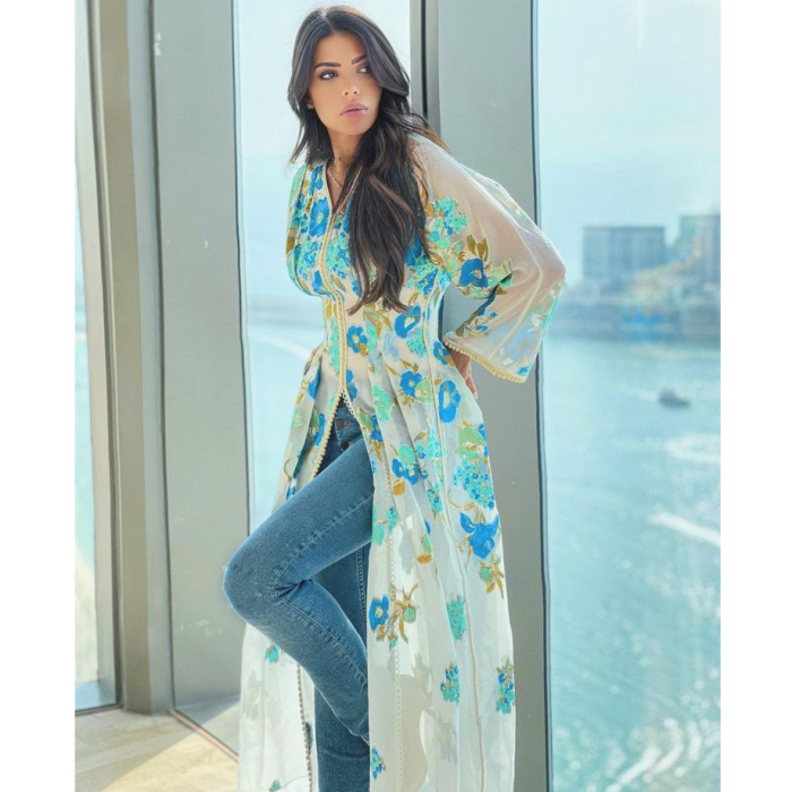 نسقت القفطان الأبيض الذي تميّز بقماشه الشفاف والمزيّن بالورود الزرقاء مع البنطلون الدنيم