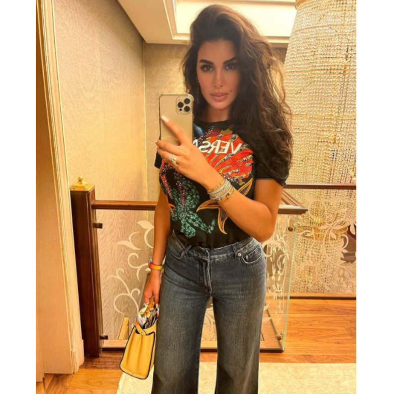 نسّقت تيشيرت من ماركة Versace مع البنطلون الدنيم بقصة الأرجل الواسعة