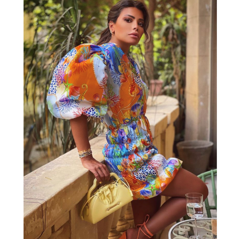 بدت بغاية الأناقة بالفستان القصير المنقوش نسّقت معه حقيبة باللون الأصفر من مجموعة OKHTEIN