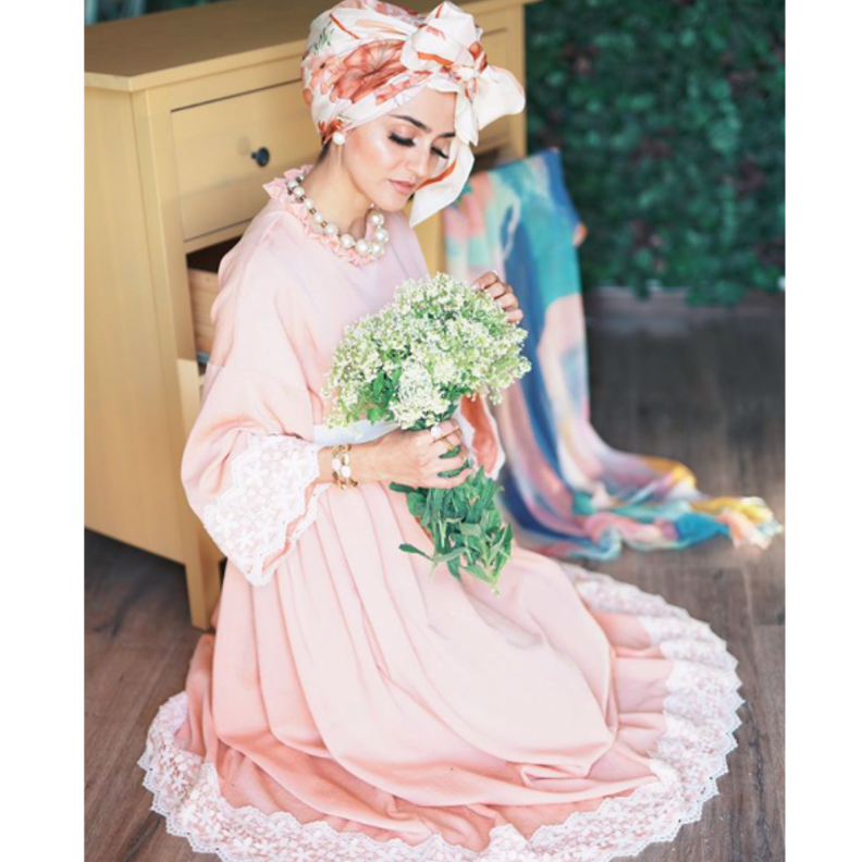 اطلالة غادة عثمان الأنثوية والجذابة بالفستان الزهري الفاتح مع لمسات من الدانتيل والتوربان الملون