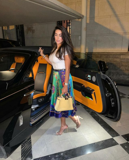 نسّقت التنورة الميدي من Versace مع التوب الأبيض وحقيبة Fendi