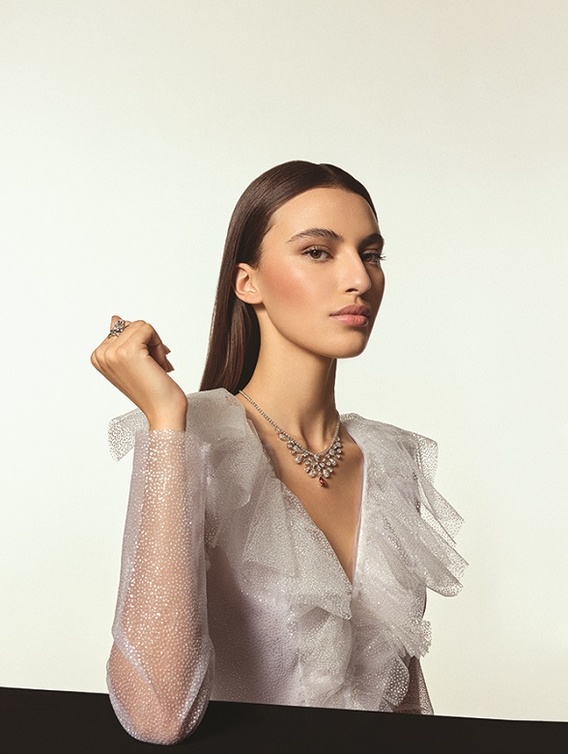 من "شوميه"Chaumet ، عقد "جوزفين إيغريت إمبيريال" Joséphine Aigrette Impériale من الذهب الأبيض المرصع بالماس، وبحجر ياقوت إجاصي القطع بعيار 2.67 قيراط؛ وخاتم "جوزفين إيغريت إمبيريال" Joséphine Aigrette Impériale من البلاتين المرصع بماسة إجاصية عيارها على الأقل 3 قراريط، وماسات دائرية متألقة.  فستان طويل الكمين من التول المزين بحبيبات براقة من "فيلوزوفي دي لورينزو سيرافيني"  Philosophy di Lorenzo Serafini.