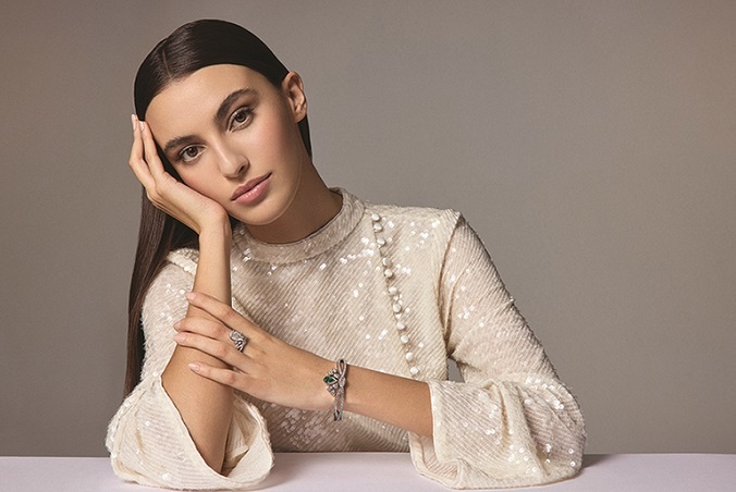 من "شوميه"Chaumet ، خاتم "جوزفين إيغريت إمبيريال" Joséphine Aigrette Impériale من البلاتين المرصع بماسة إجاصية عيارها على الأقل 3 قراريط وماسات دائرية متألقة، وسوار "جوزفين إيغريت إمبيريال" Joséphine Aigrette Impériale من البلاتين والذهب الأبيض، ومرصع بماسات دائرية متألقة، وزمردة إجاصية عيارها على الأقل 1.5 قيراط.  فستان واسع الكمين مكسو بالترترة ومزين بأزرار جانبية من "إيلتا"Ilta .